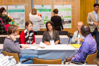 A group of people sit at a table and collaborate over a poster during a workshop