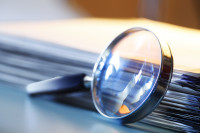 A metal magnifying glass leans against a stack of papers