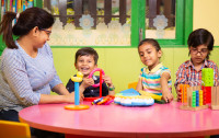 Preschool children learning toy blocks from teacher 