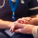 Elderly person with hands held by health professional