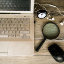 Image of a laptop computer, mouse, headphones, clock