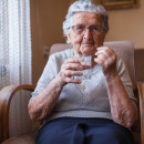 Older person taking medicine at home with a glass of water