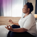 Person sitting on a bed doing meditation