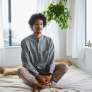 Young man meditating alone in his bedroom at home stock photo