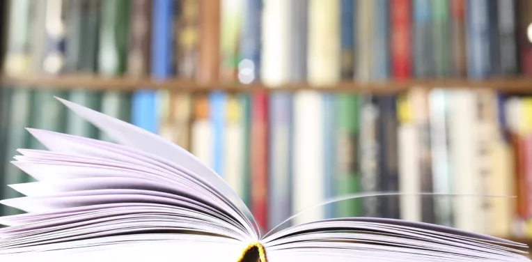 An open book in front of a library shelf