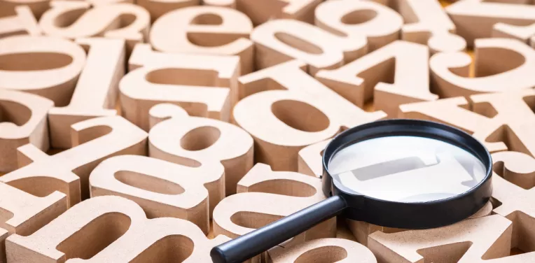 Magnifying glass on many English alphabet wood letters