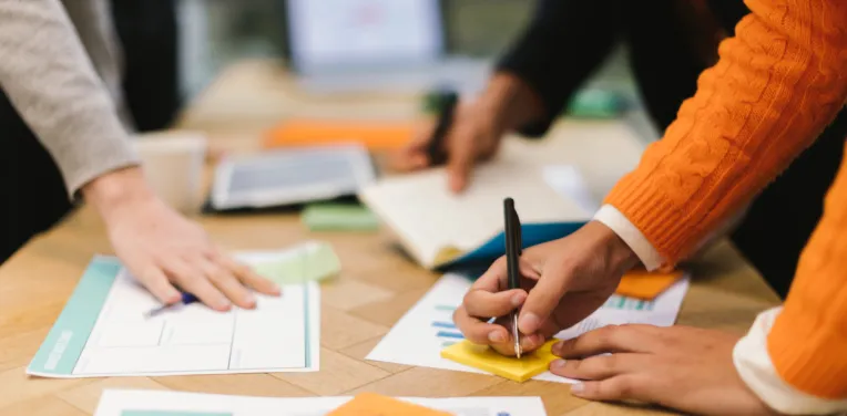 hands of colleagues working on projects using paper data and writing notes