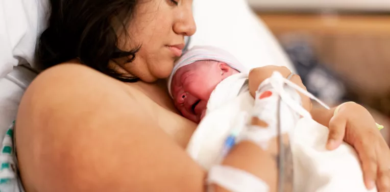 Author Jessica Hatcher-Moore with her first baby at home, days after giving birth. Jessica had a positive first experience of birth but felt poorly prepared for what came next. Image: © Philip Hatcher-Moore