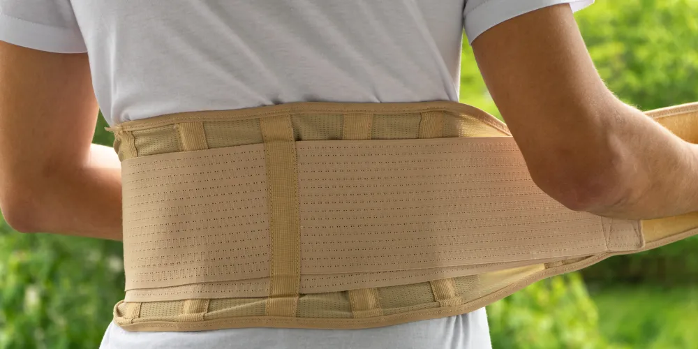 A teenager puts on an orthopaedic corset or back brace.