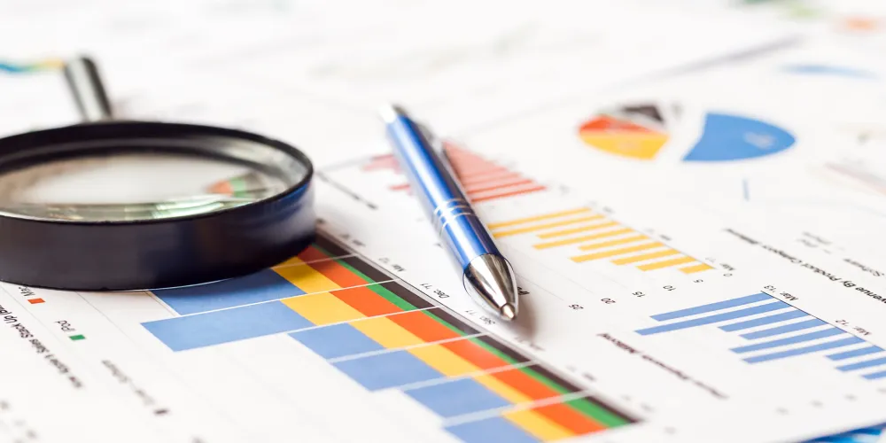 Magnifier and pen on charts graphs paper