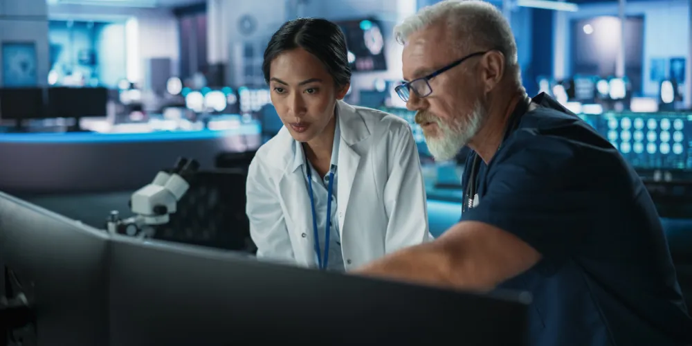 Two clinicians analyze data on a computer screen