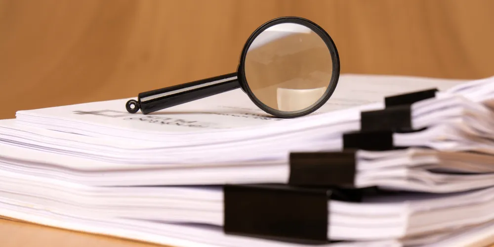 A magnifying glass rests on scattered clipped papers