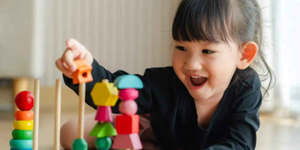 Happy Asian child playing with bricks. 