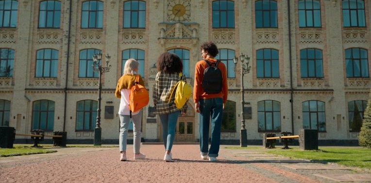 three students walking towards a university building